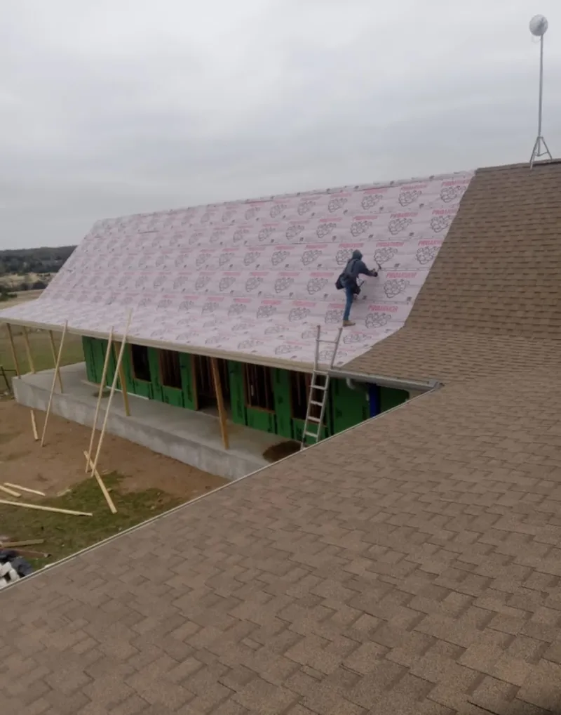 Worker preparing underlayment for a metal roof installation in Jamestown